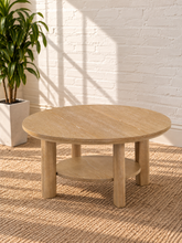 Load image into Gallery viewer, Image 4 of 5: Vito round coffee table in Sunwashed Oak with sculpted legs, circular lower shelf, and natural wood-grain finish