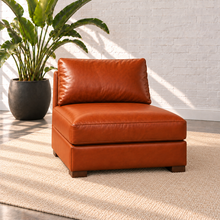 Load image into Gallery viewer, Image 8 of 14: Simulated Hollis 31-inch armless modular chair in Mont Blanc Caramel leather, open on both sides with one seat and back cushion, styled on a plain ivory rug beside a bird-of-paradise plant.