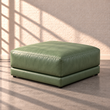 Load image into Gallery viewer, Image 14 of 18: Simulated Orinda individual bumper ottoman module in sage green Sequoia Rainforest leather, without accent pillows, in the Sunbeam white brick setting.