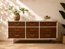 Load image into Gallery viewer, Vintage Asian Modern Campaign style nine-drawer walnut dresser with white trim, curved brass hardware, brass corner details and tapered legs.
