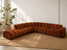 Load image into Gallery viewer, Large rust brown velvet modular sectional sofa with sculptural channel tufting, curved corner, chaise and dark wood plinth base.
