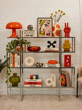 Load image into Gallery viewer, Vintage chrome and glass étagère styled with 1970s Pop Art books, colorful sculptural ceramics, retro lighting, and graphic decor.

