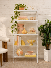 Load image into Gallery viewer, Tall white metal étagère with five glass shelves, open geometric frame, and X-brace side detailing.
