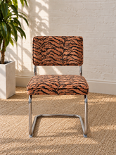 Load image into Gallery viewer, Modern 70s-style dining chair with terracotta and black tiger-print upholstery and polished chrome cantilever frame
