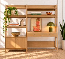 Load image into Gallery viewer, A light natural wood writing desk and shelving unit set against a white brick wall, styled with books, a green plant, a green dome lamp, and an art print.
