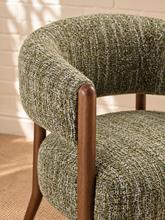 Load image into Gallery viewer, Abby accent chair upholstered in textured sage amber bouclé with curved wraparound backrest, cushioned seat and exposed brown wood legs.
