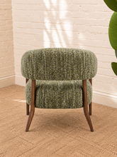 Load image into Gallery viewer, Abby accent chair upholstered in textured sage amber bouclé with curved wraparound backrest, cushioned seat and exposed brown wood legs.
