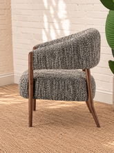 Load image into Gallery viewer, Abby charcoal grey textured bouclé accent chair with curved wraparound backrest, cushioned seat and exposed brown solid wood legs.
