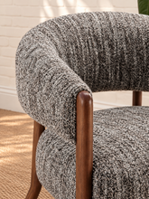 Load image into Gallery viewer, Abby charcoal grey textured bouclé accent chair with curved wraparound backrest, cushioned seat and exposed brown solid wood legs.
