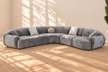 Load image into Gallery viewer, Aela curved sectional sofa upholstered in textured ash grey fabric with rounded corners, square arms, tight back, and five toss pillows.
