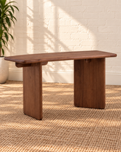 Load image into Gallery viewer, Alijah sculptural desk in natural brown mindi wood with rounded rectangular top, asymmetrical slab legs, and curved under-top supports. 
