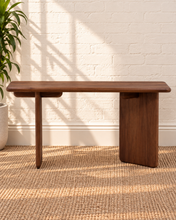 Load image into Gallery viewer, Alijah sculptural desk in natural brown mindi wood with rounded rectangular top, asymmetrical slab legs, and curved under-top supports.
