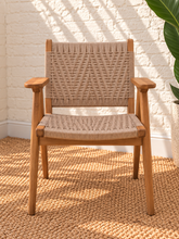 Load image into Gallery viewer, Alma natural teak wood dining armchair with tall synthetic rope woven back, woven seat, and curved wooden armrests.
