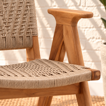 Load image into Gallery viewer, Alma natural teak wood dining armchair with tall synthetic rope woven back, woven seat, and curved wooden armrests.
