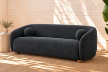 Load image into Gallery viewer, Amara slate navy curved sofa with textured upholstery, rounded arms, ball accent pillows, and wood bun feet
