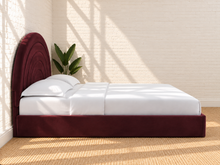 Load image into Gallery viewer, Astrid King-size bed in Burgundy performance velvet with sculptural arched headboard and streamlined plinth base.
