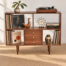 Load image into Gallery viewer, Mid-century modern walnut record console with open vinyl storage, three center drawers, tapered legs, and a styled turntable display.
