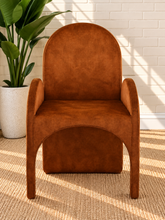Load image into Gallery viewer, Bailey upholstered dining chair in Burnt Cognac velvet with curved arms and sculptural contemporary frame
