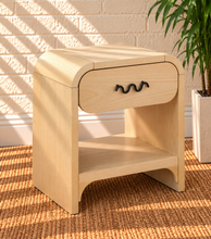 Load image into Gallery viewer, Byron Blonde Oak wood nightstand with curved frame, drawer, matte black metal handle, and open lower shelf.
