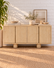 Load image into Gallery viewer, Cailah natural light reclaimed pine wood credenza with four cabinet doors, subtle wood grain, interior shelving, and rounded pedestal legs.

