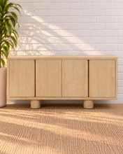 Load image into Gallery viewer, Cailah natural light reclaimed pine wood credenza with four cabinet doors, subtle wood grain, interior shelving, and rounded pedestal legs.

