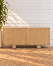 Load image into Gallery viewer, Cailah natural light reclaimed pine wood credenza with four cabinet doors, subtle wood grain, interior shelving, and rounded pedestal legs.


