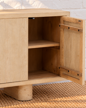 Load image into Gallery viewer, Cailah natural light reclaimed pine wood credenza with four cabinet doors, subtle wood grain, interior shelving, and rounded pedestal legs.

