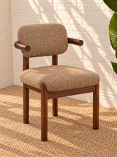 Load image into Gallery viewer, Caroline dining chair upholstered in toffee brown burlap fabric with curved wraparound back, rounded arms, and Mindi wood legs.
