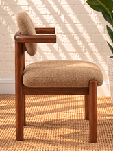 Load image into Gallery viewer, Caroline dining chair upholstered in toffee brown burlap fabric with curved wraparound back, rounded arms, and Mindi wood legs.
