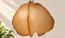 Load image into Gallery viewer, Claire hanging lamp in warm camel resin with an organic sculptural shade, overlapping curved forms, textured surface, and dark cord suspension.
