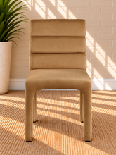 Load image into Gallery viewer, Shop the Conrad Dining Chair in Honey Cognac, featuring luxurious velvet upholstery, a deep channel-tufted back, and a sculptural contemporary silhouette.
