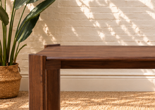 Load image into Gallery viewer, Darius rectangular dining table in natural brown Mindi wood veneer with wide panel legs and visible wood grain.
