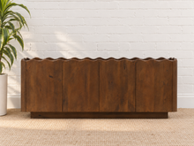 Load image into Gallery viewer, Eden natural brown mango wood credenza with sculptural wave-edged detailing, paneled cabinet doors, concealed shelving, and recessed plinth base.

