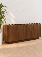 Load image into Gallery viewer, Eden natural brown mango wood credenza with sculptural wave-edged detailing, paneled cabinet doors, concealed shelving, and recessed plinth base.

