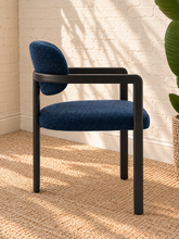 Load image into Gallery viewer, Ezra midnight blue textured upholstered dining armchair with rounded back, open silhouette, and black metal frame
