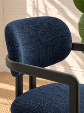 Load image into Gallery viewer, Ezra midnight blue textured upholstered dining armchair with rounded back, open silhouette, and black metal frame
