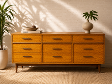 Load image into Gallery viewer, Vintage mid-century nine-drawer dresser with highly figured golden Madagascar wood, dark elongated pulls and tapered legs.
