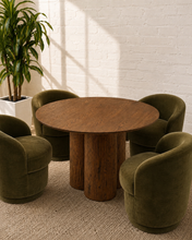 Load image into Gallery viewer, Modern round oak dining table with warm wood grain and sculptural triple-cylinder pedestal base.

