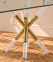 Load image into Gallery viewer, Flavia rectangular glass dining table with tempered glass top and sculptural X-shaped base in gold metal and clear acrylic.
