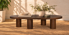 Load image into Gallery viewer, Henry solid oak coffee table in Natural Brown with organic rounded tabletop, four cylindrical legs, and prominent natural wood grain.
