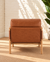 Load image into Gallery viewer, Hilario lounge chair in toasted cognac faux leather with solid ash wood frame and rounded wooden arms
