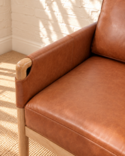 Load image into Gallery viewer, Hilario lounge chair in toasted cognac faux leather with solid ash wood frame and rounded wooden arms
