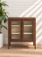 Load image into Gallery viewer, Hilda warm walnut bar cabinet with two tempered glass doors, recessed finger pulls, light interior shelves, and tapered wood legs
