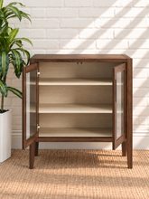 Load image into Gallery viewer, Hilda warm walnut bar cabinet with two tempered glass doors, recessed finger pulls, light interior shelves, and tapered wood legs
