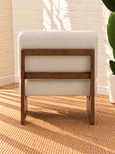 Load image into Gallery viewer, Karyl Ivory armless accent chair with ivory tufted upholstery, removable cushions and sculptural walnut-finished oak wood frame.
