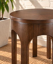 Load image into Gallery viewer, Kaylee sculptural side table in natural brown with a round top and arched Art Deco-inspired base.

