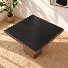 Load image into Gallery viewer, Kenji square dining table with inset black tempered glass top, walnut wood veneer border, and substantial square pedestal base.
