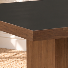 Load image into Gallery viewer, Kenji square dining table with inset black tempered glass top, walnut wood veneer border, and substantial square pedestal base.
