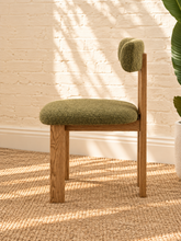 Load image into Gallery viewer, Kiki dining chair with avocado green bouclé upholstered seat and backrest, high-density foam cushioning and natural solid ash wood frame.
