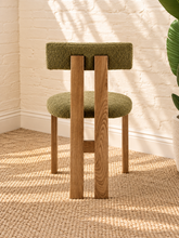 Load image into Gallery viewer, Kiki dining chair with avocado green bouclé upholstered seat and backrest, high-density foam cushioning and natural solid ash wood frame.
